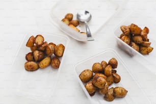 three plastic containers filled with potatoes on top of a table
