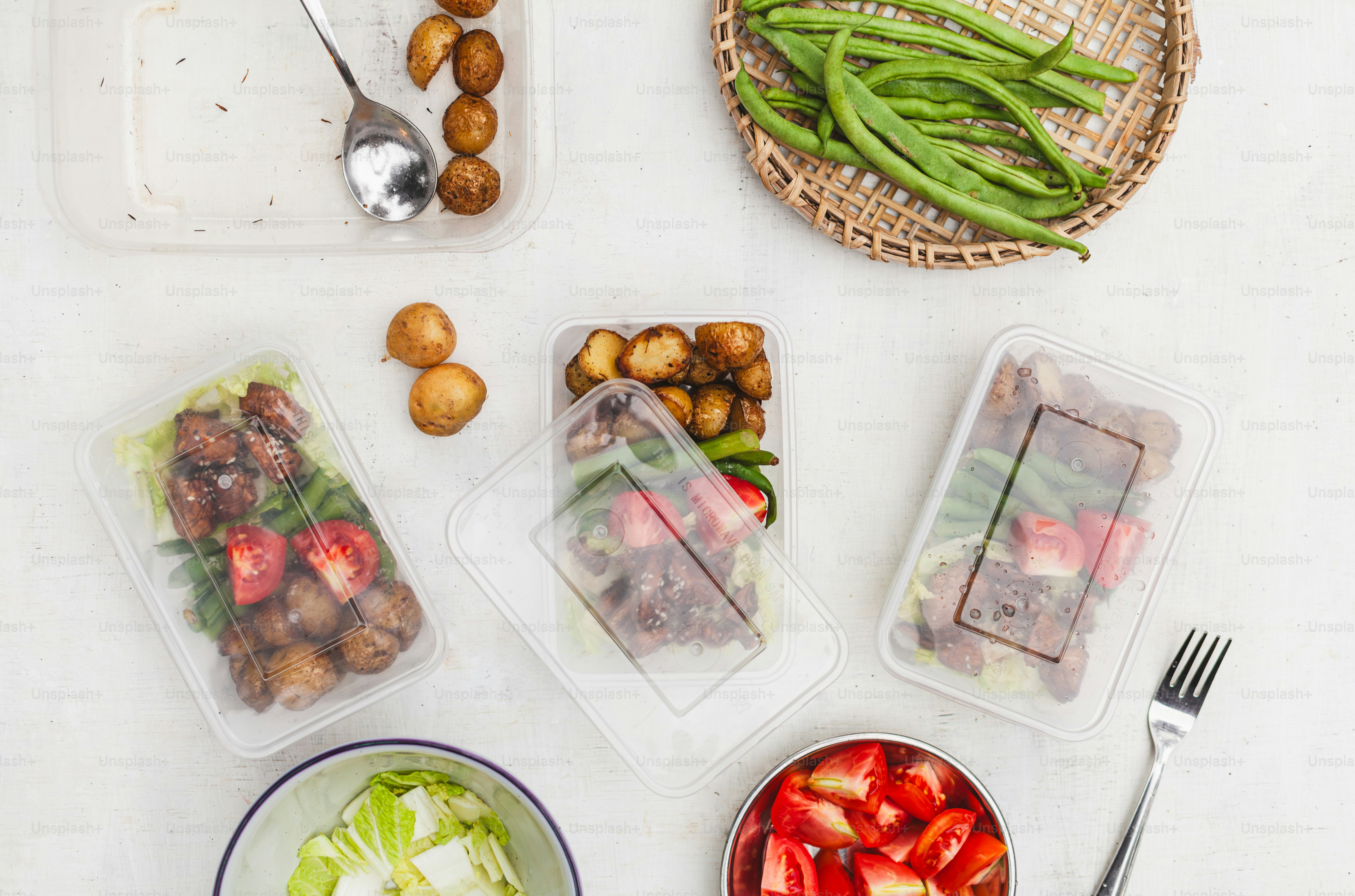a table topped with plastic containers filled with food