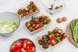 a table topped with plastic containers filled with food