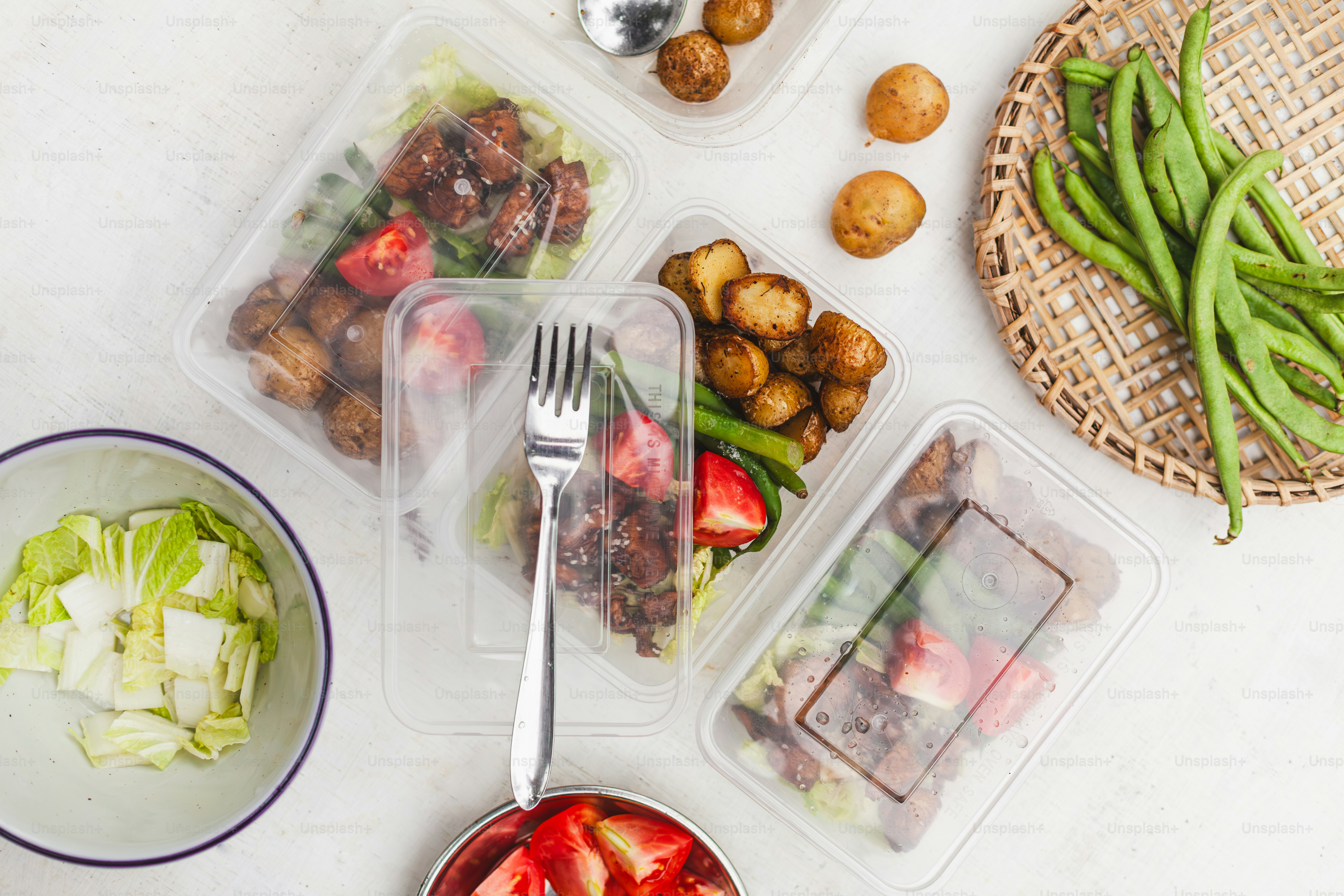 a table topped with plastic containers filled with food