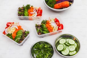 four plastic containers filled with different types of vegetables
