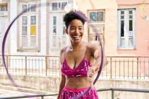 a woman in a pink dress is spinning a hoop