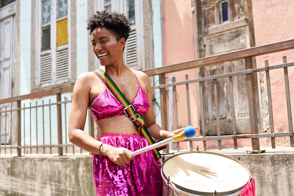 a woman in a pink outfit holding a drum