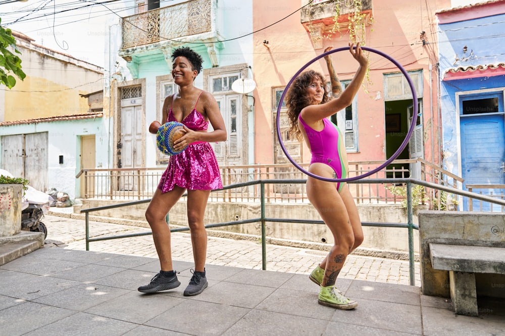 two young women are playing with a hoop