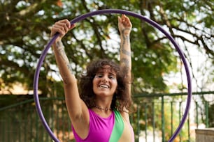 a woman in a purple tank top is holding a purple hula hoop