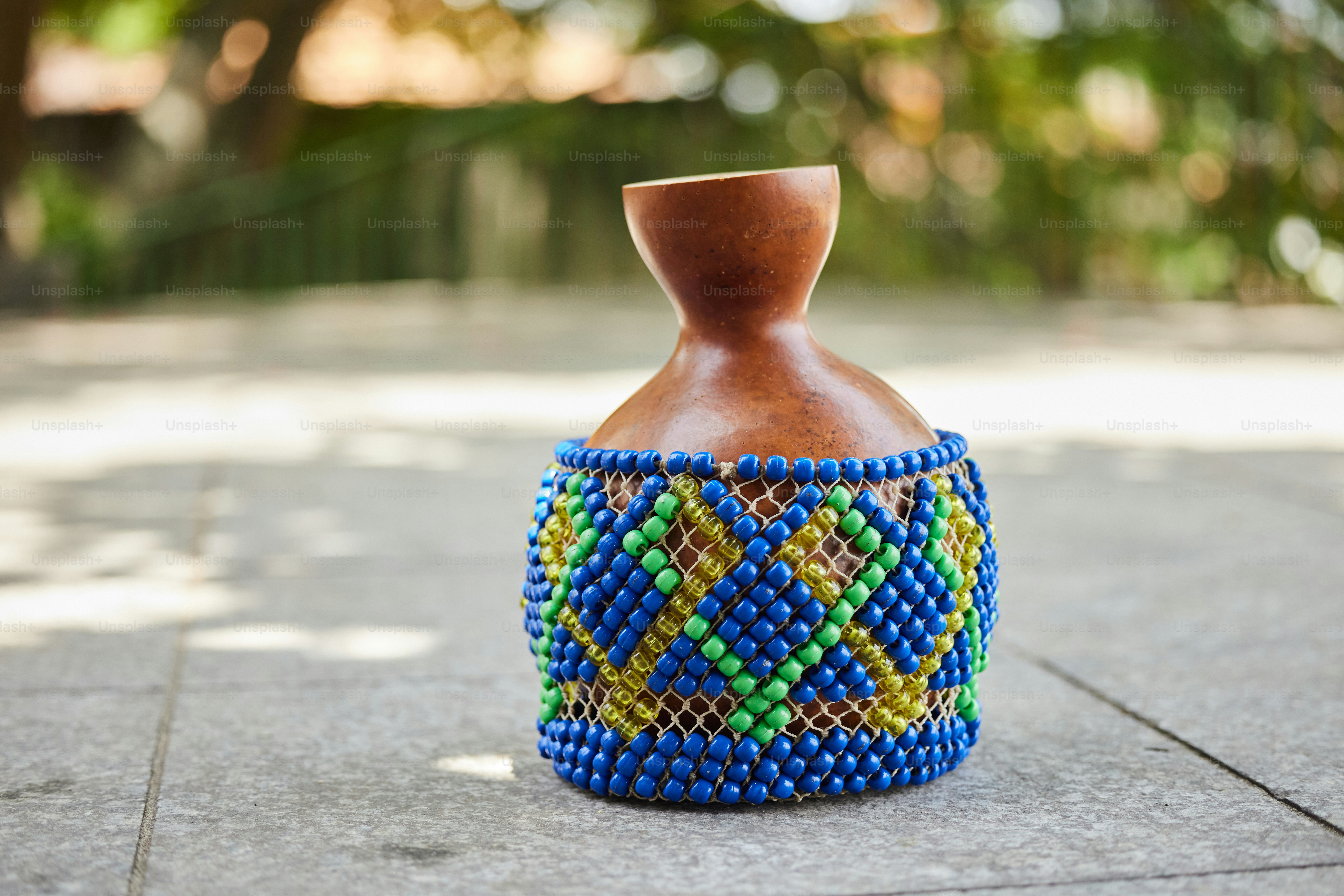 a blue and green vase sitting on top of a sidewalk