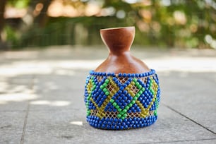 a blue and green vase sitting on top of a sidewalk