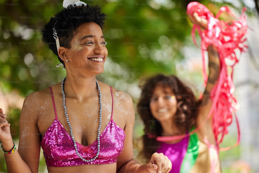 Eine Frau in einem rosa Bikinioberteil steht neben einer anderen Frau in einem lila Bikini