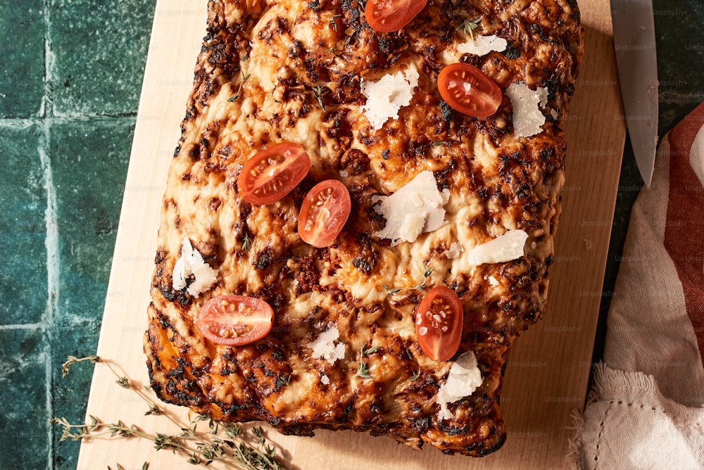 a pizza with tomatoes and cheese on a cutting board