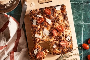 a pizza with tomatoes and cheese on a cutting board