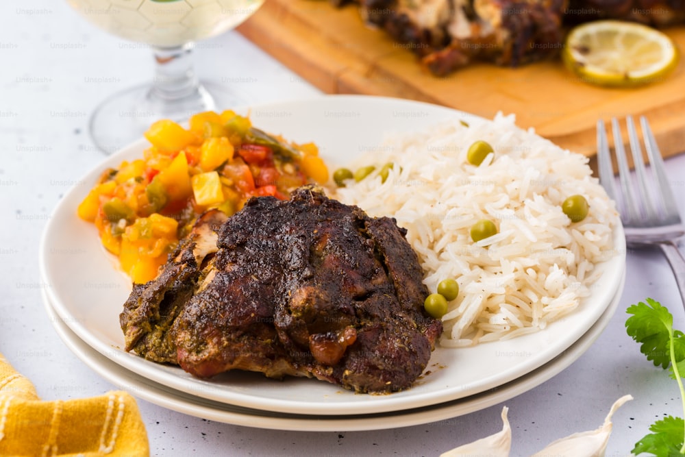 a white plate topped with meat and rice next to a glass of wine