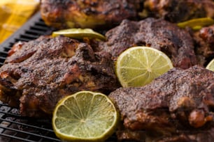 a close up of a grill with meat and lemons