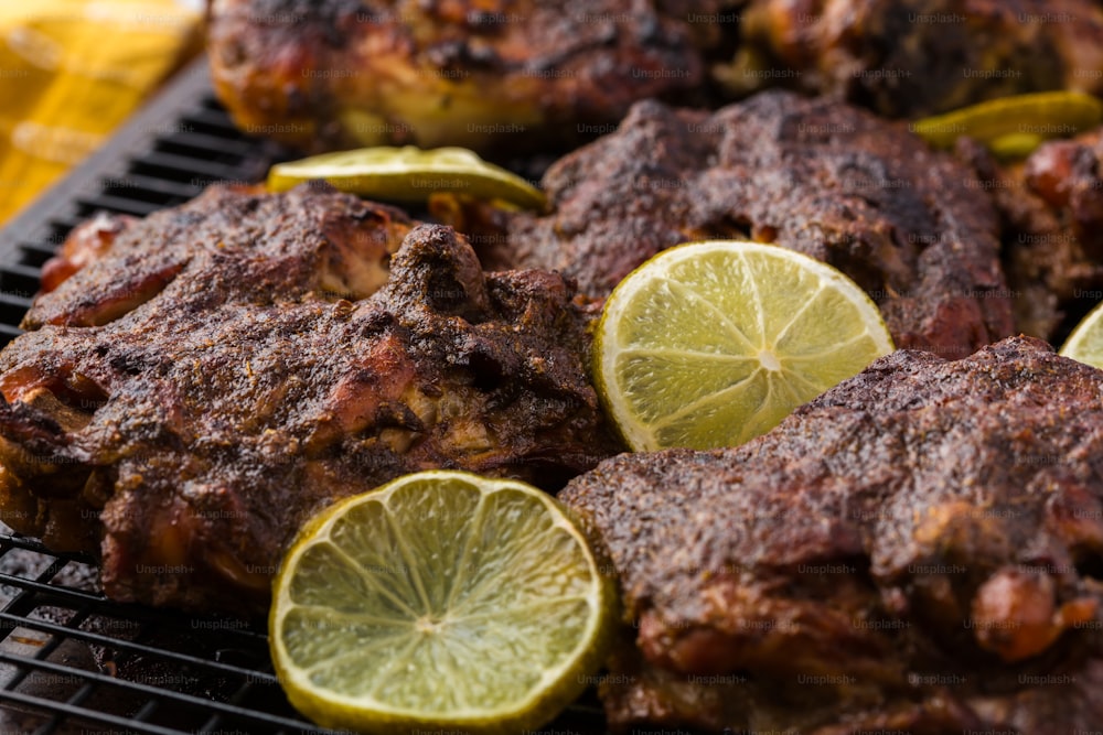 a close up of a grill with meat and lemons