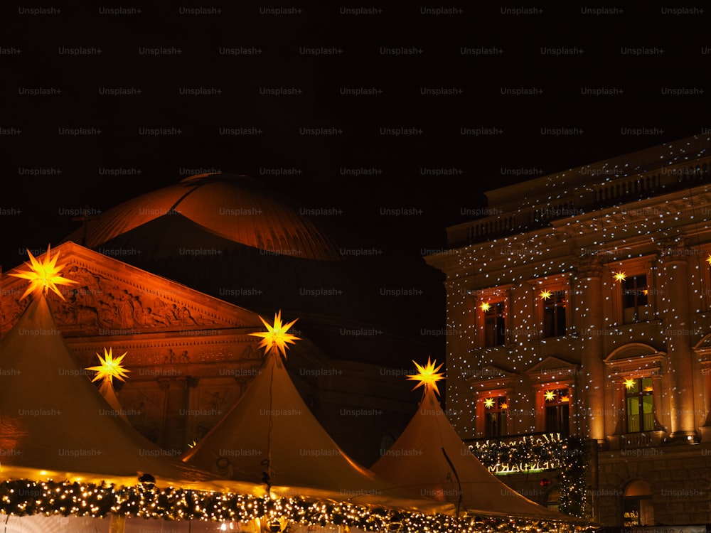 a large tent with lights on it in front of a building