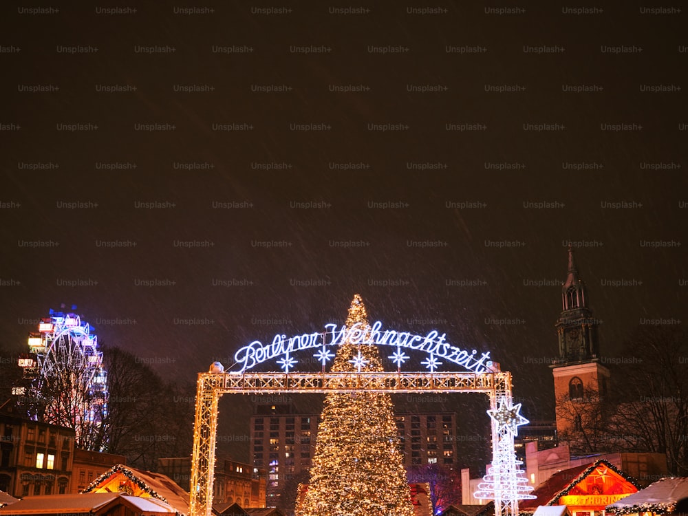 Uma grande árvore de Natal é iluminada em frente a um edifício