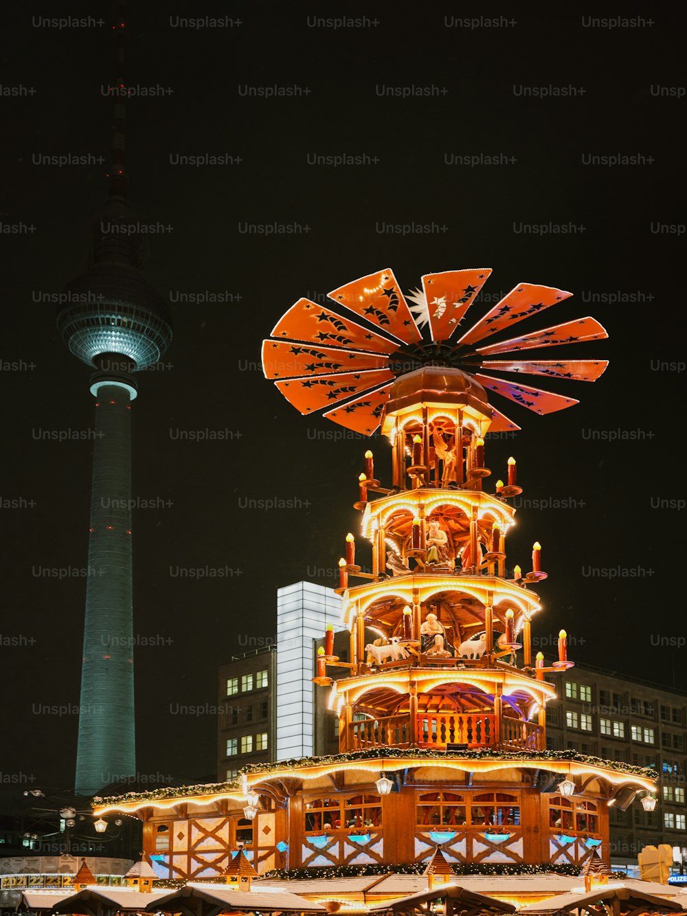uma roda-gigante iluminada à noite em frente a um prédio alto