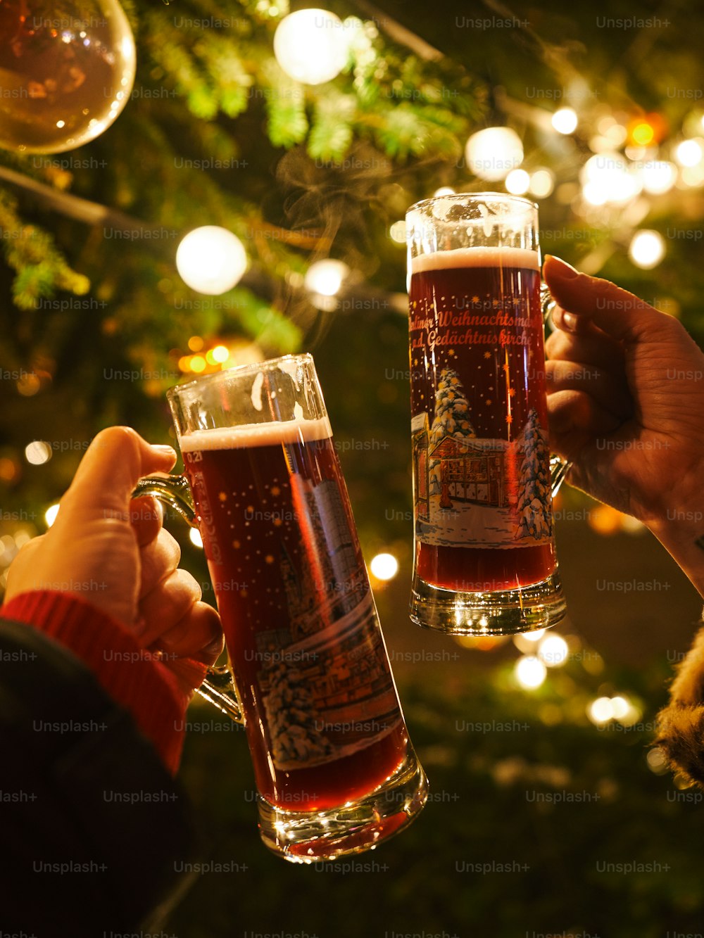 two people toasting with beer in front of a christmas tree