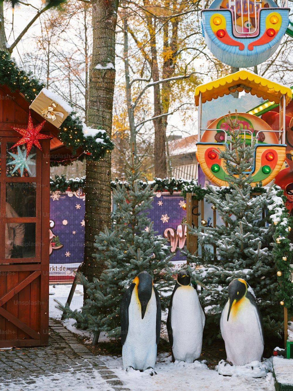 a group of penguins standing next to a christmas tree