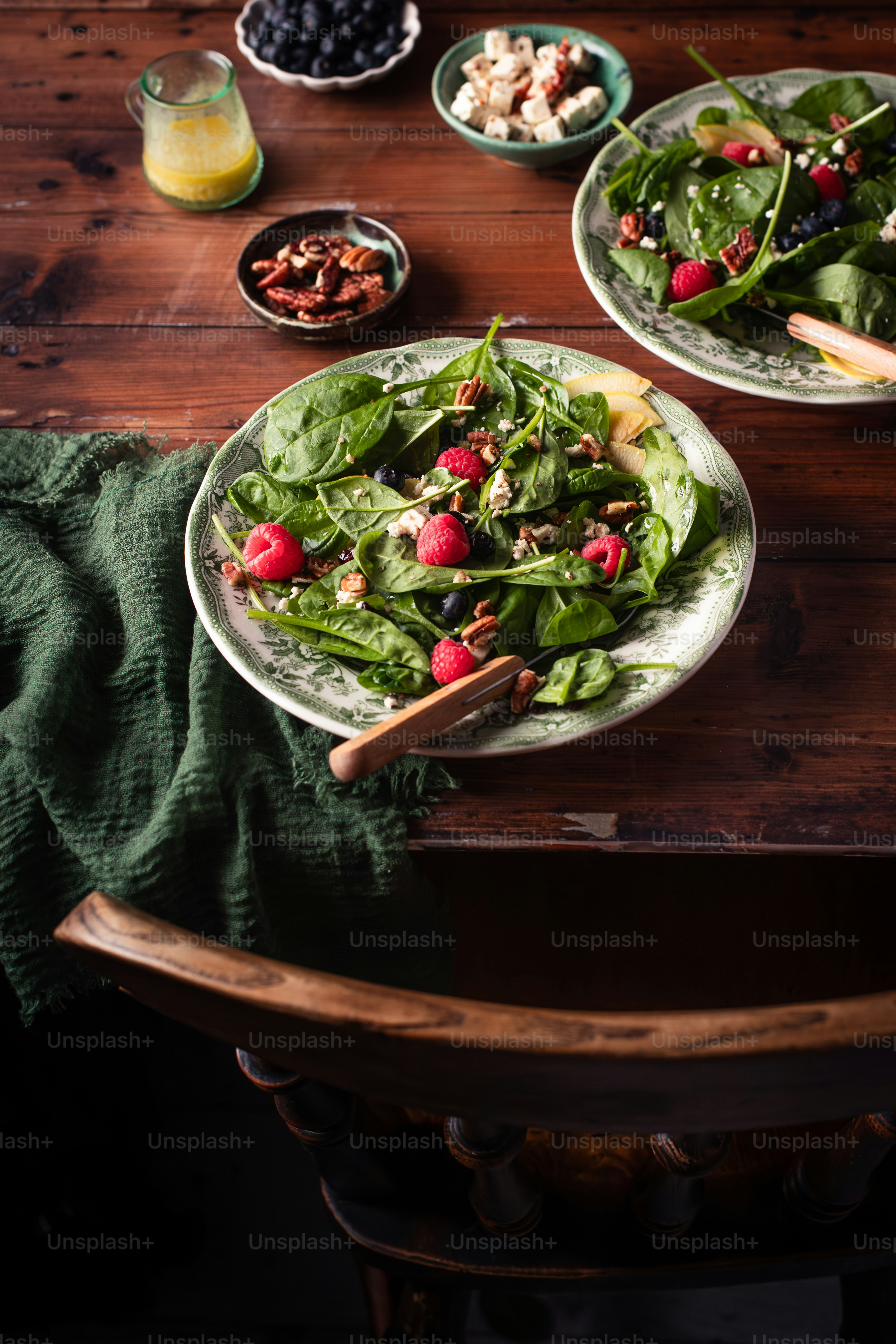 a wooden table topped with plates of salad