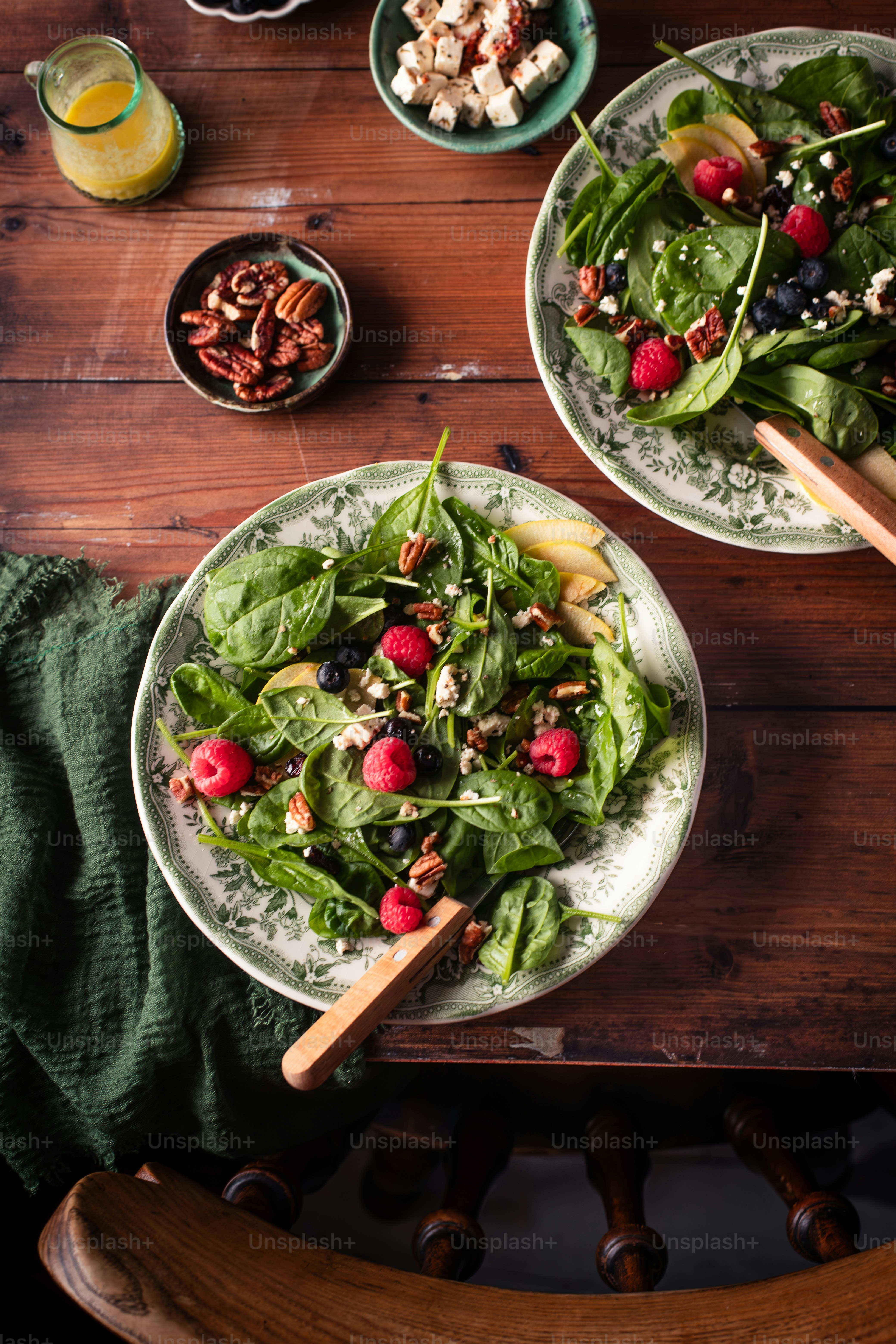 a wooden table topped with two plates of salad