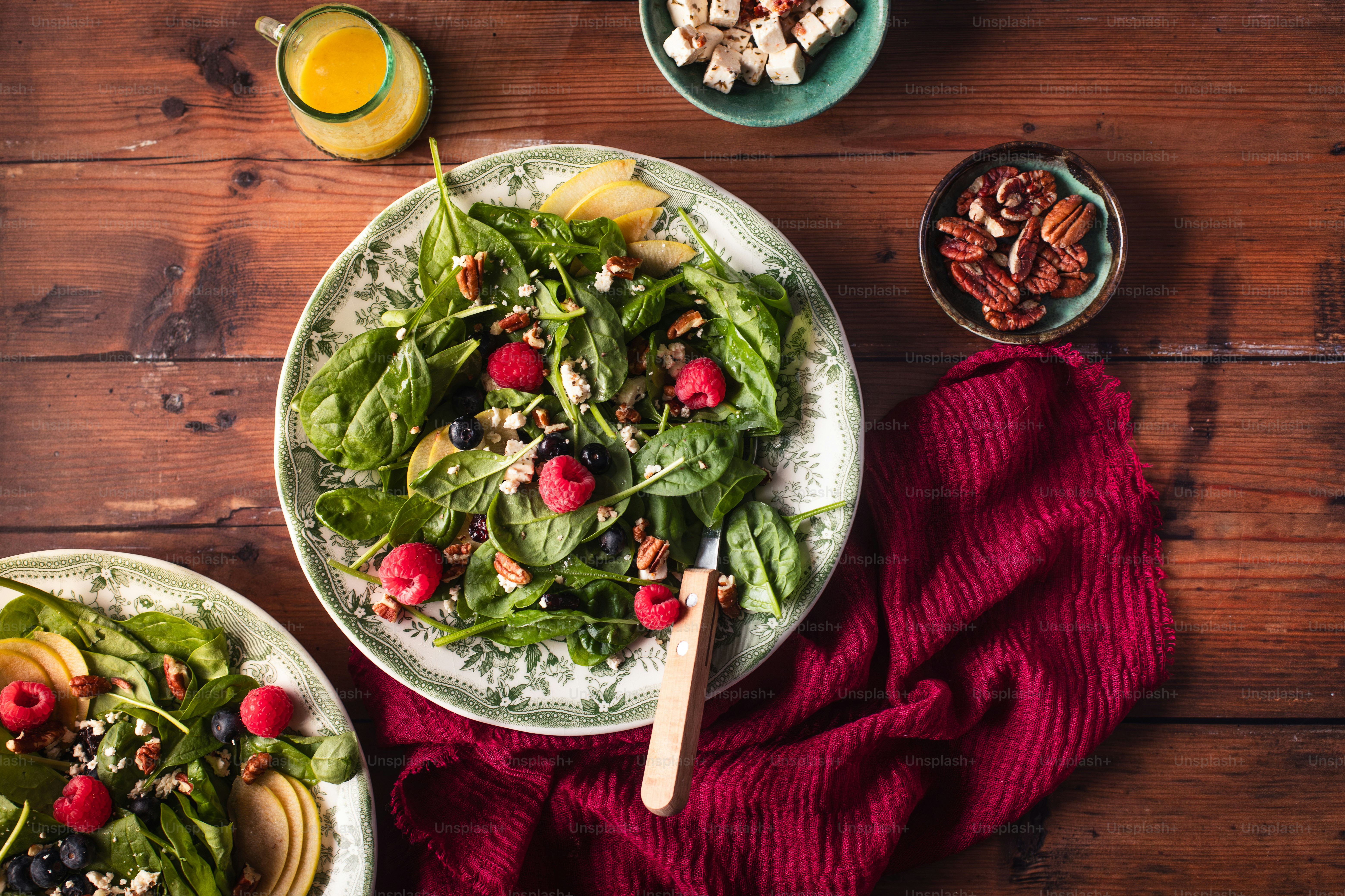 two plates of salad and a glass of orange juice