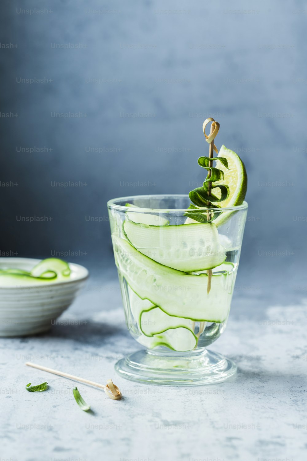 a glass filled with cucumber and a slice of lime