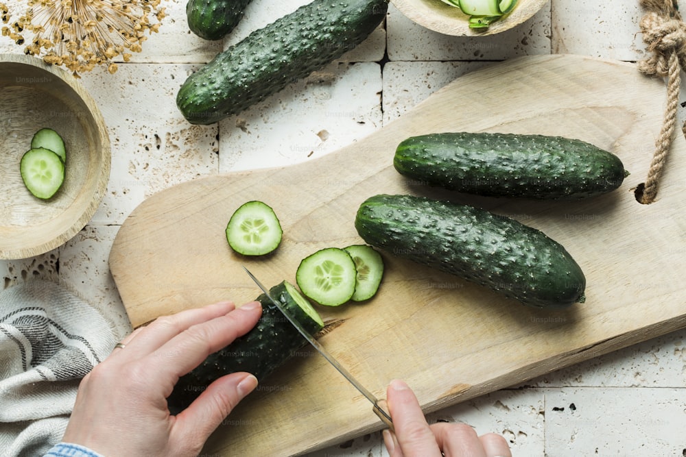 a person cutting cucumbers on a cutting board