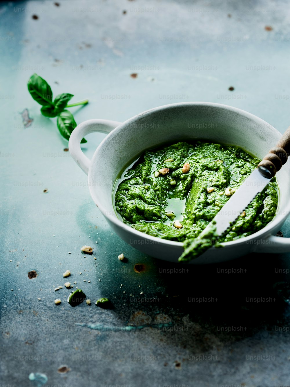 a bowl of pesto with a knife in it