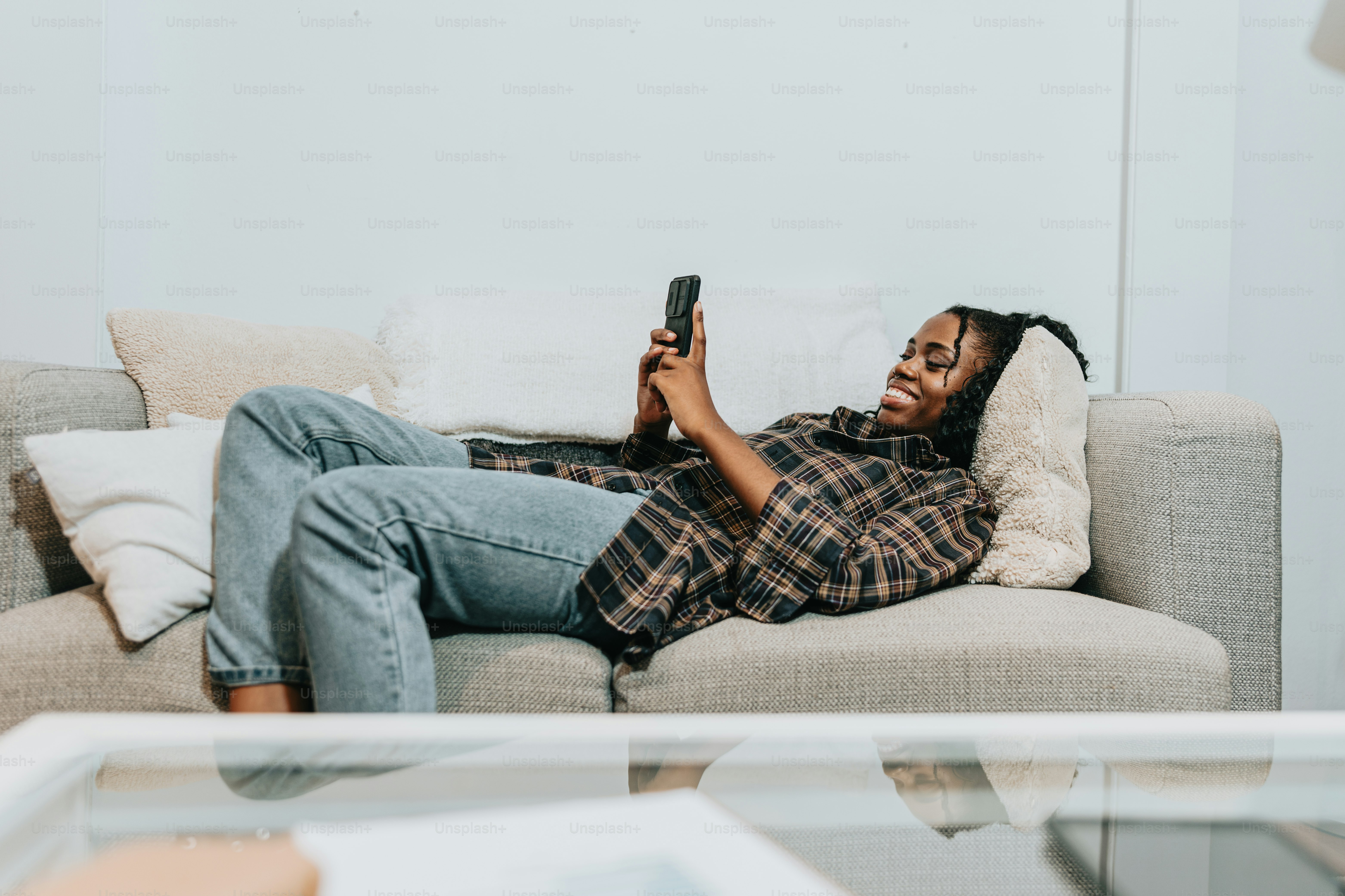 a woman laying on a couch holding a cell phone