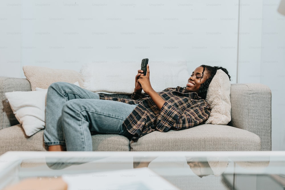 a woman laying on a couch holding a cell phone