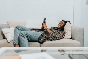 a woman laying on a couch holding a cell phone