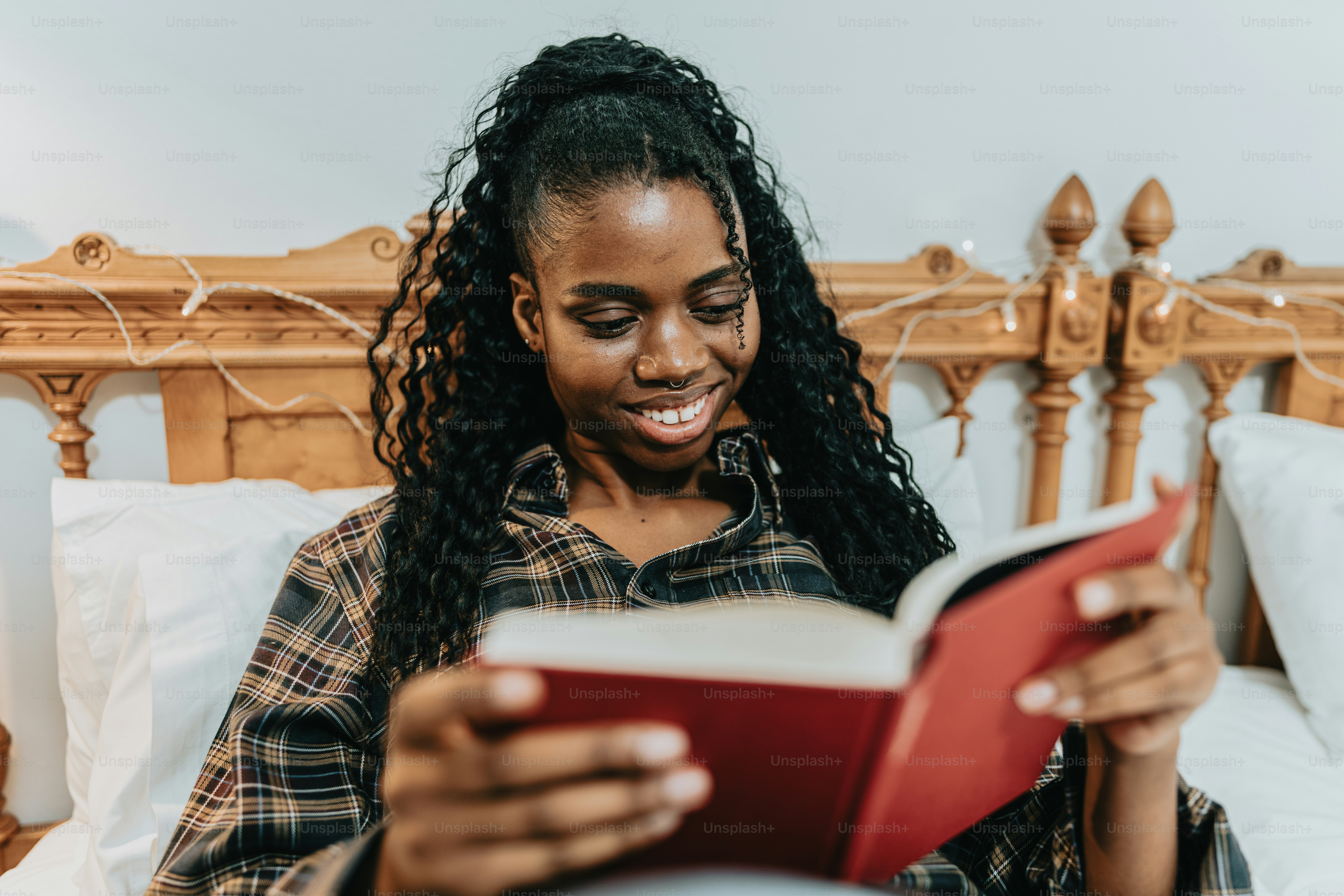 a woman sitting on a bed reading a book
