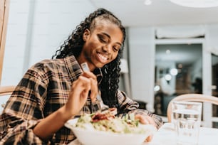 a woman sitting at a table eating a salad