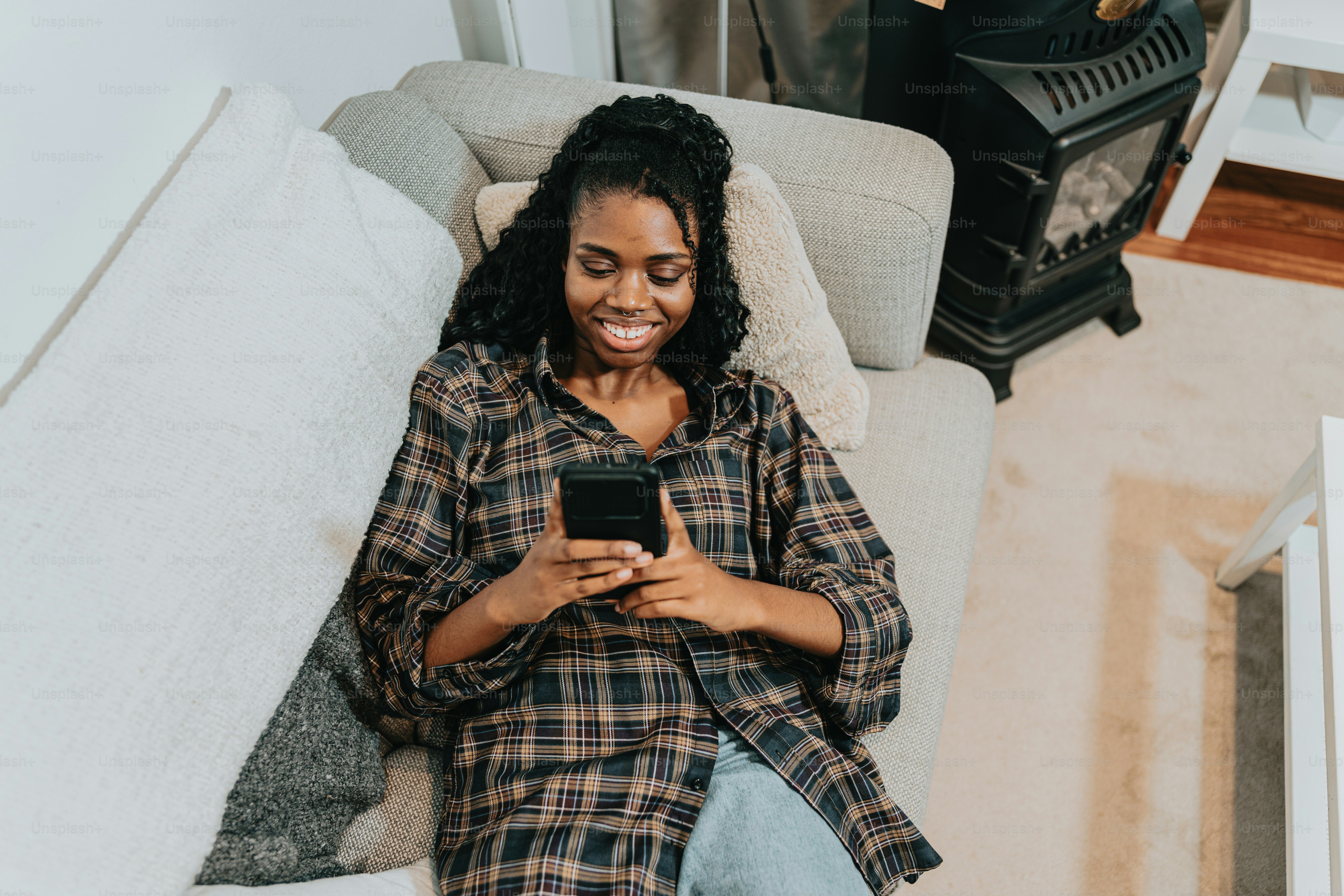 a woman sitting on a couch using a cell phone