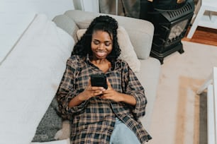 uma mulher sentada em um sofá usando um telefone celular