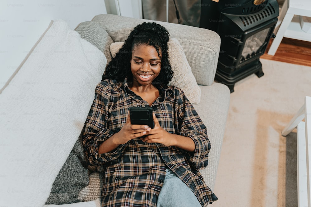 a woman sitting on a couch using a cell phone