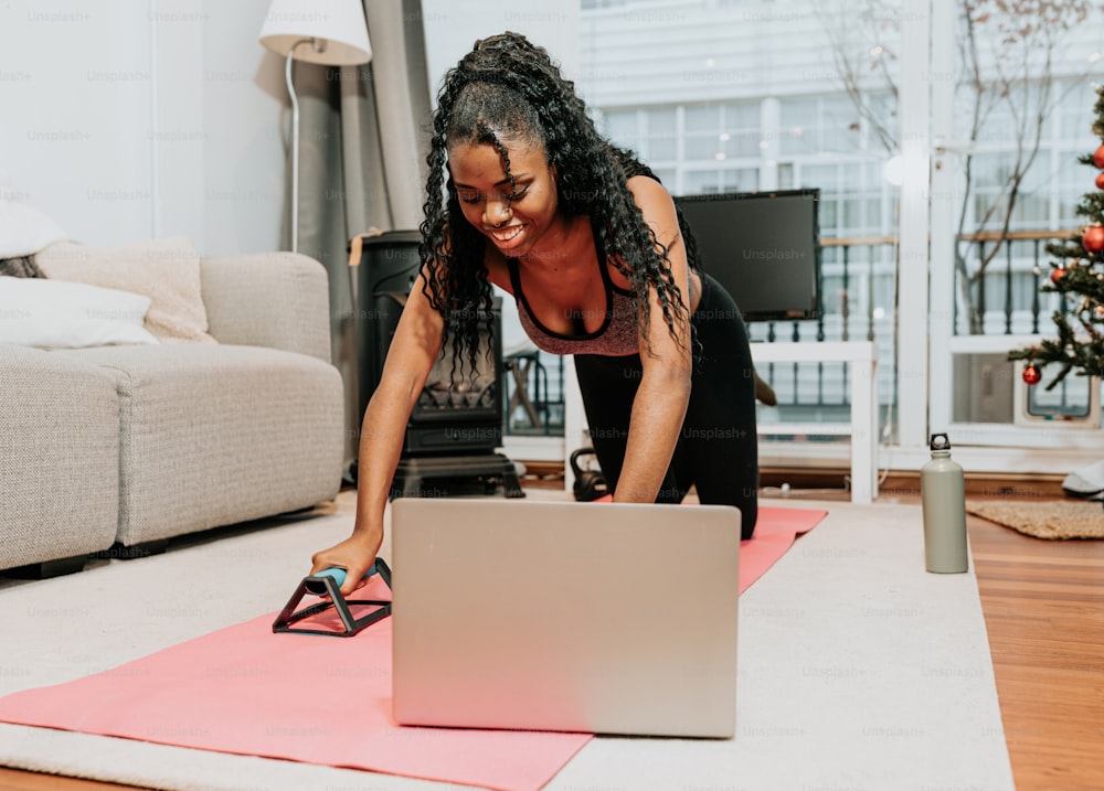 a woman on a yoga mat using a laptop computer