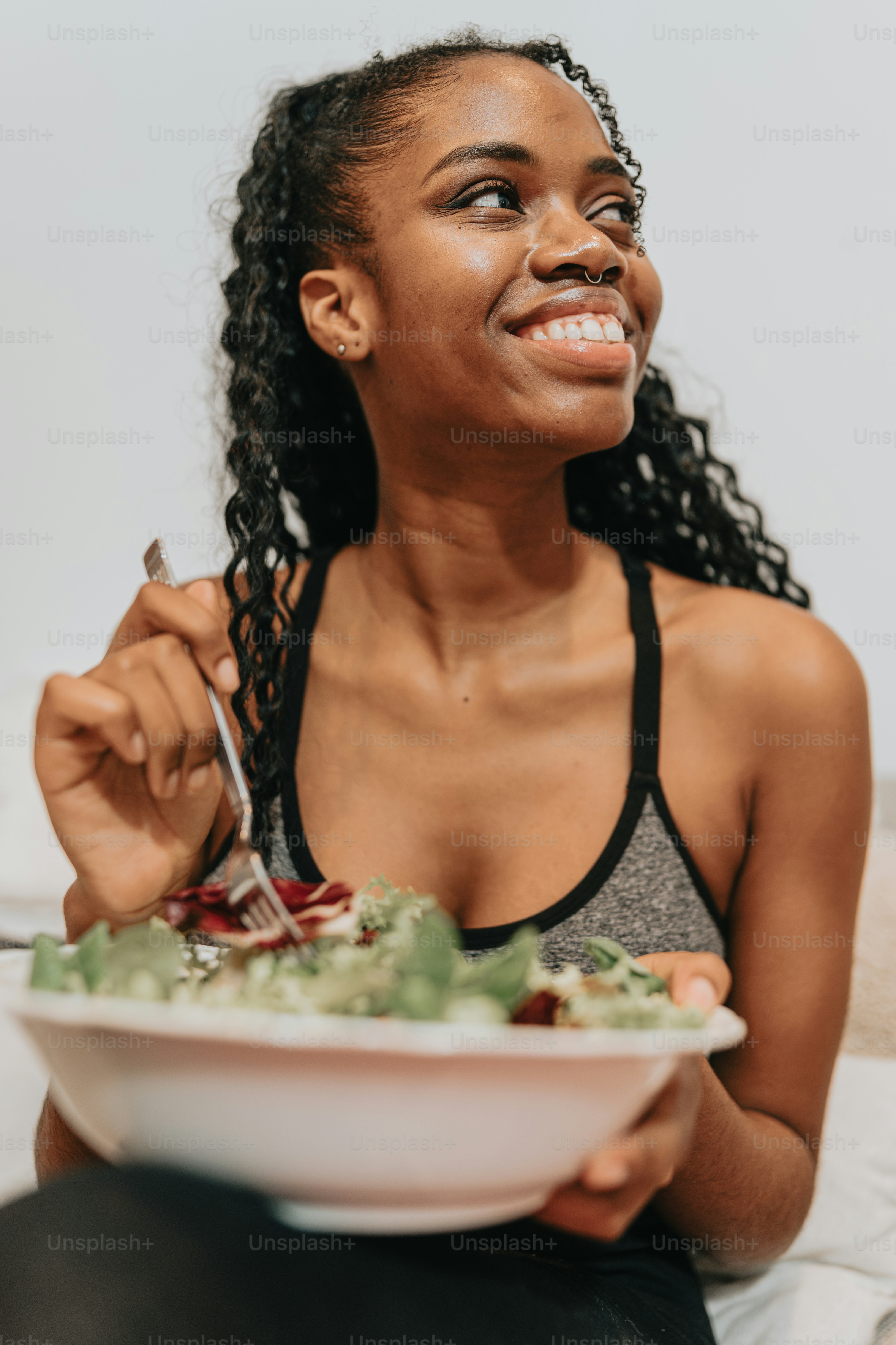 a woman sitting on a couch eating a salad
