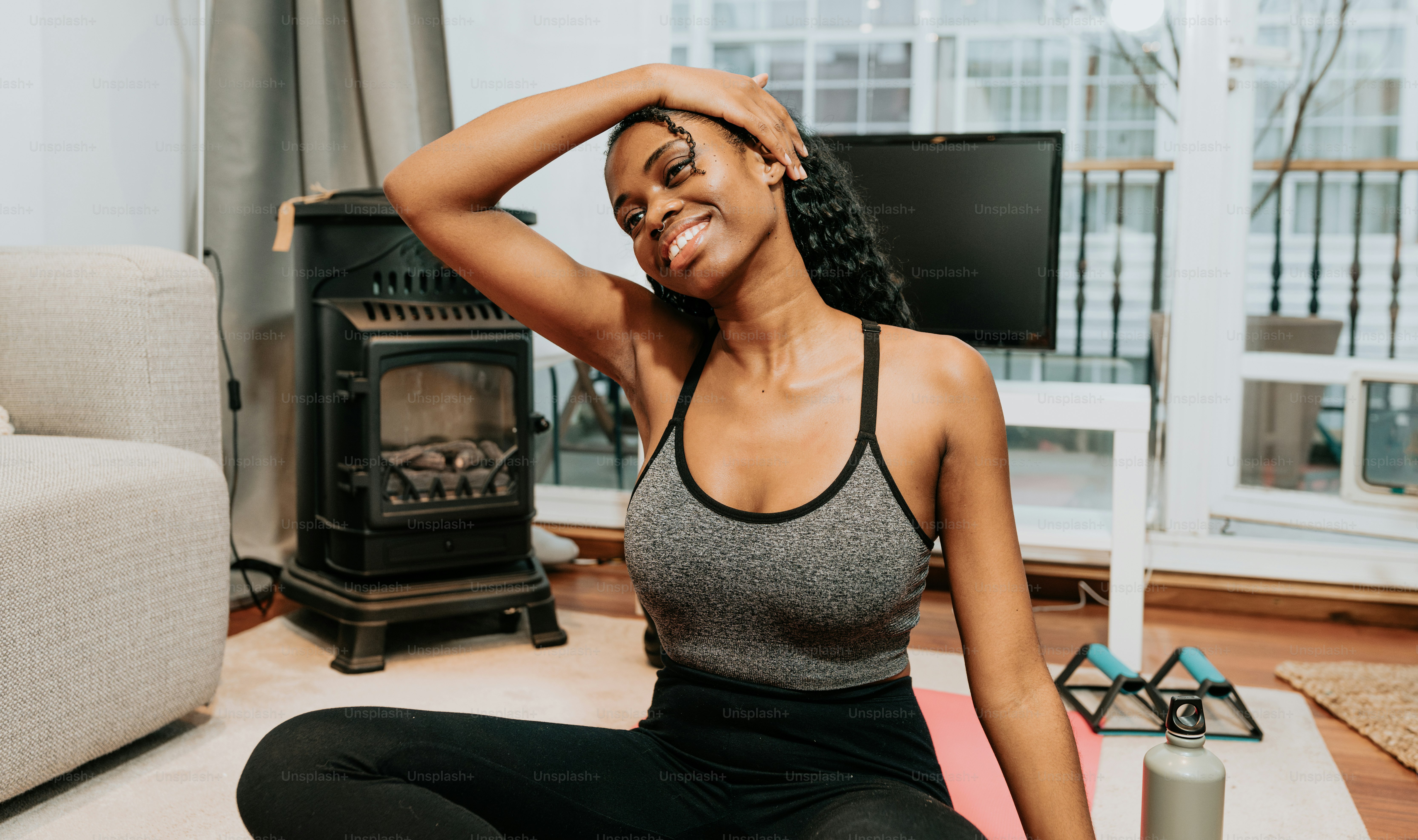 a woman sitting on a yoga mat in a living room