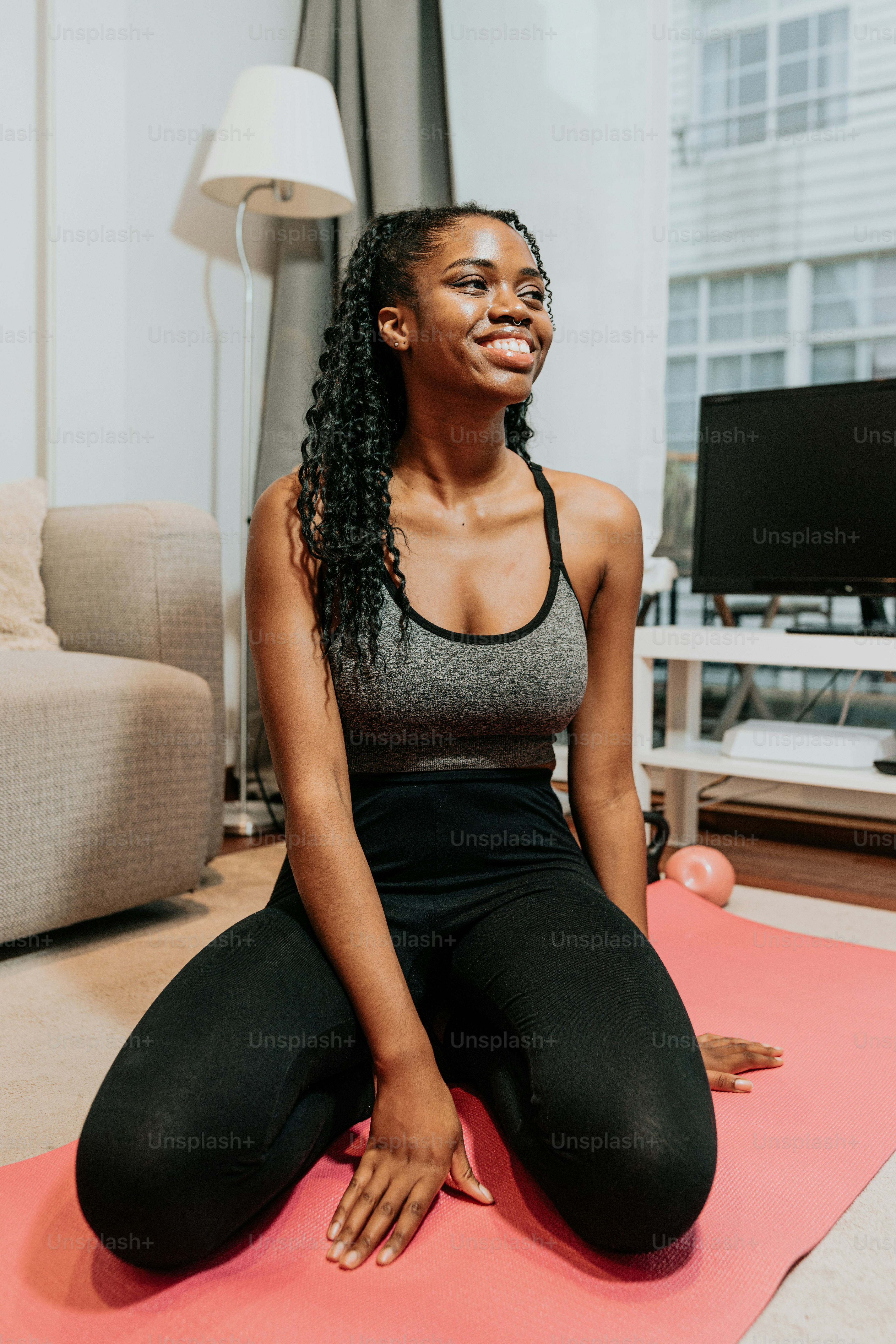 a woman sitting on a yoga mat in a living room