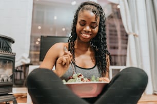 a woman sitting on the floor eating a salad