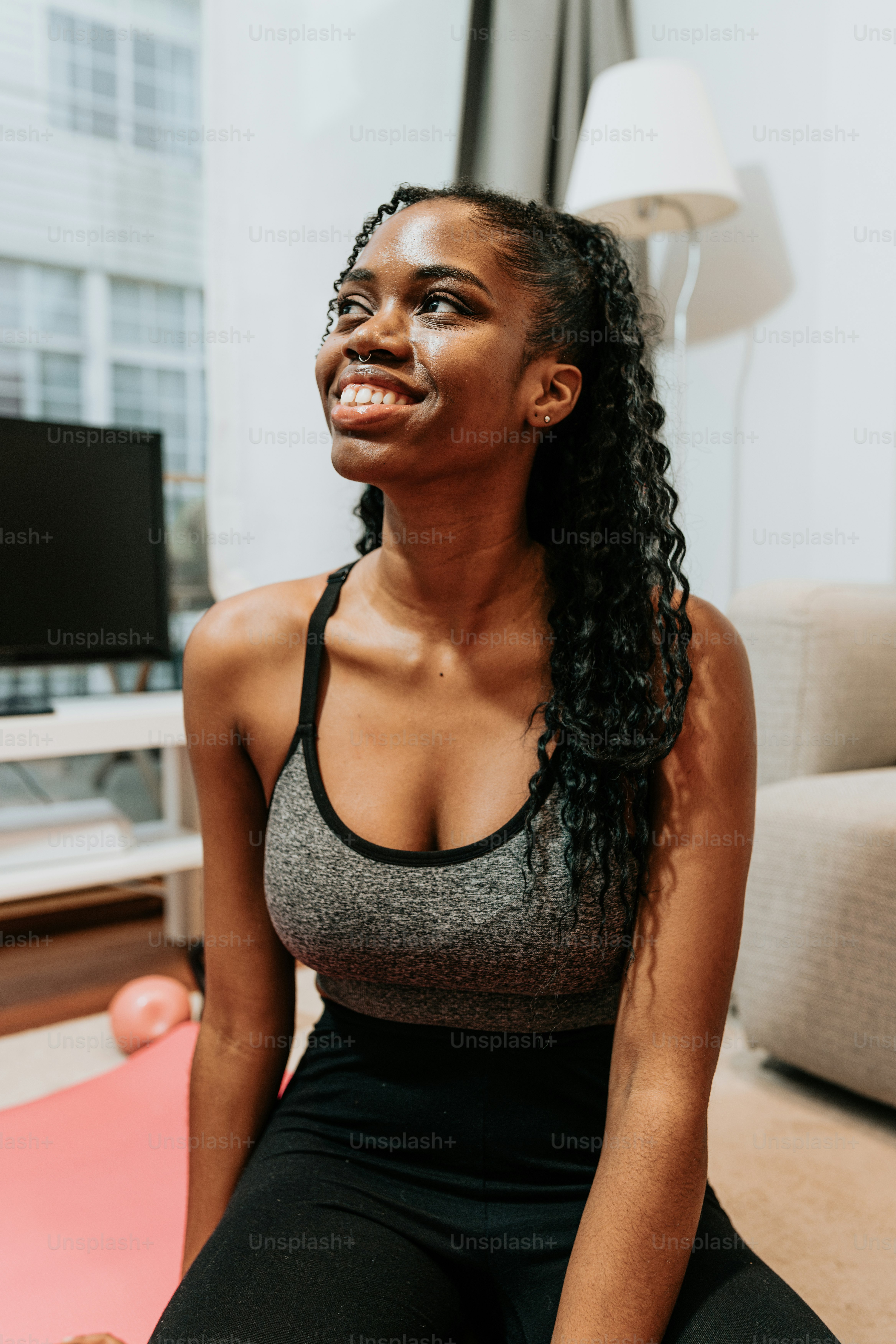 A woman sitting on a yoga mat in a living room photo – Food Image on ...