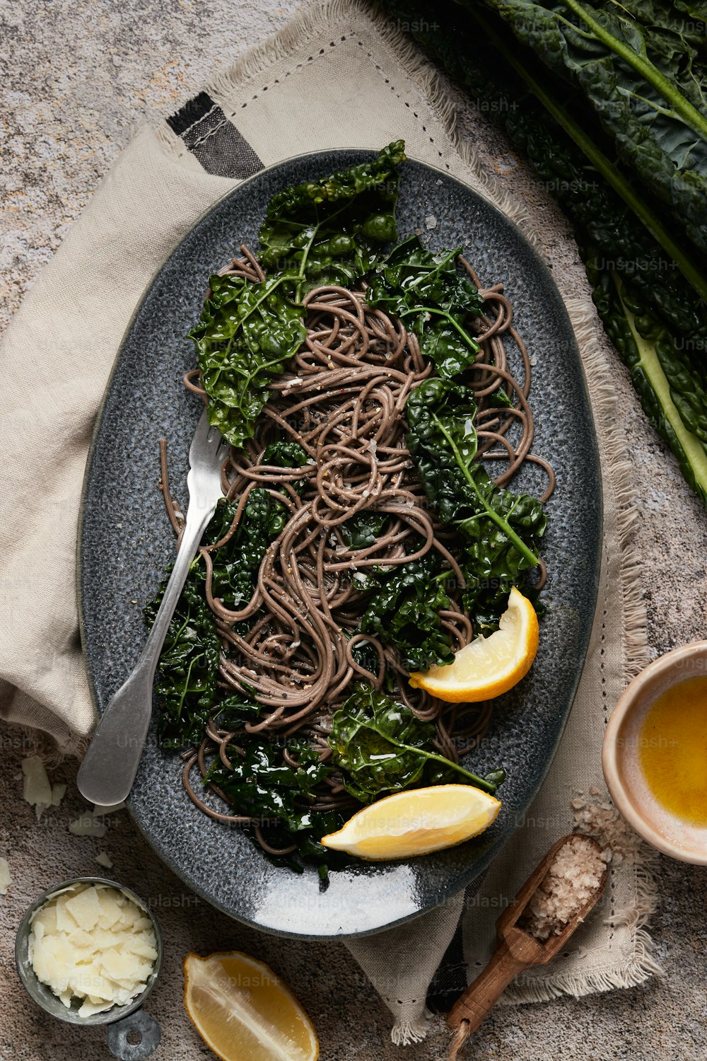 a plate of noodles with greens and lemons