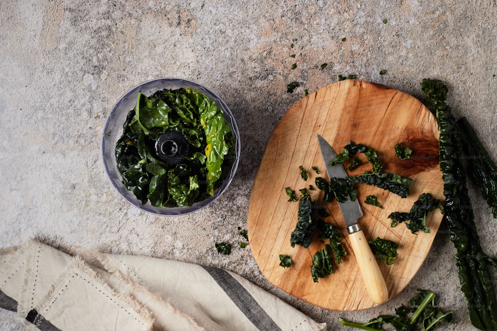 una tabla de cortar cubierta con verduras junto a un cuchillo