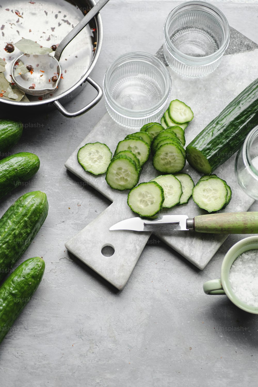 a cutting board topped with cucumbers and a knife