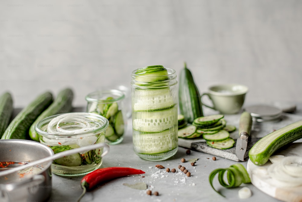 a table topped with jars filled with cucumbers