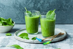 two glasses of green smoothie on a plate