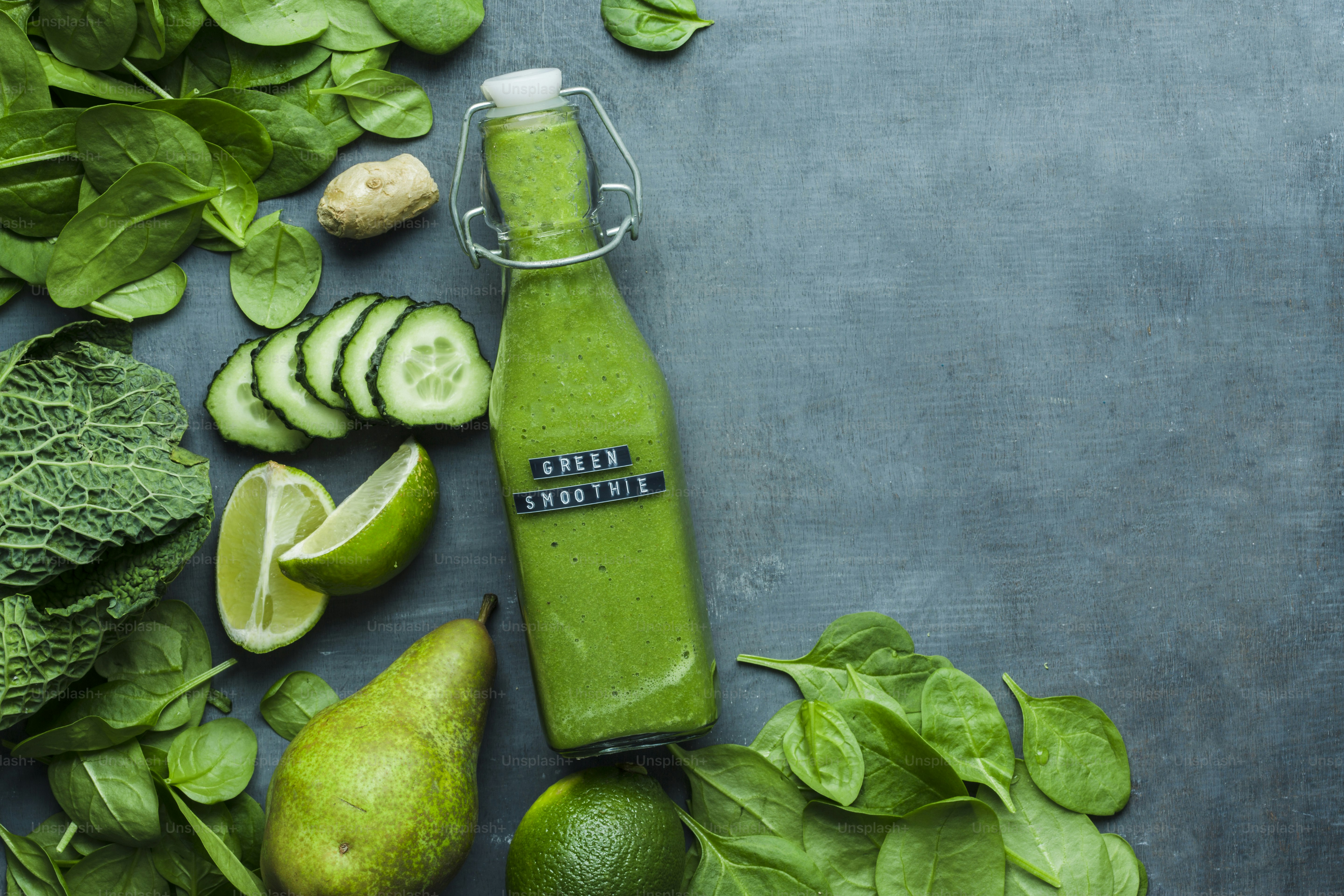smoothie hijau dalam botol yang dikelilingi oleh buah-buahan dan sayuran
