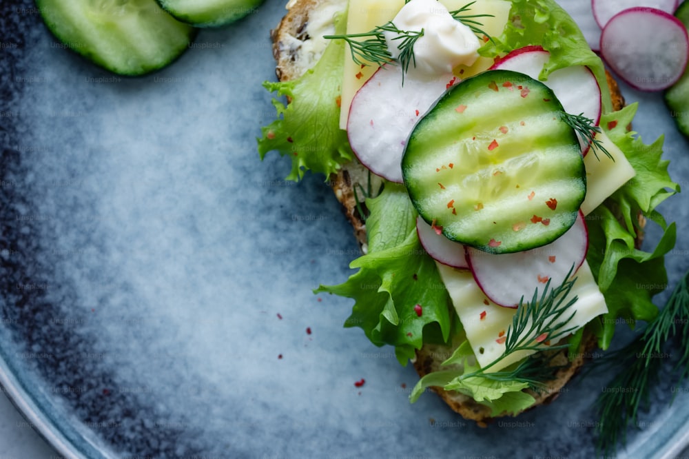 a sandwich with cucumbers, radishes, and cheese