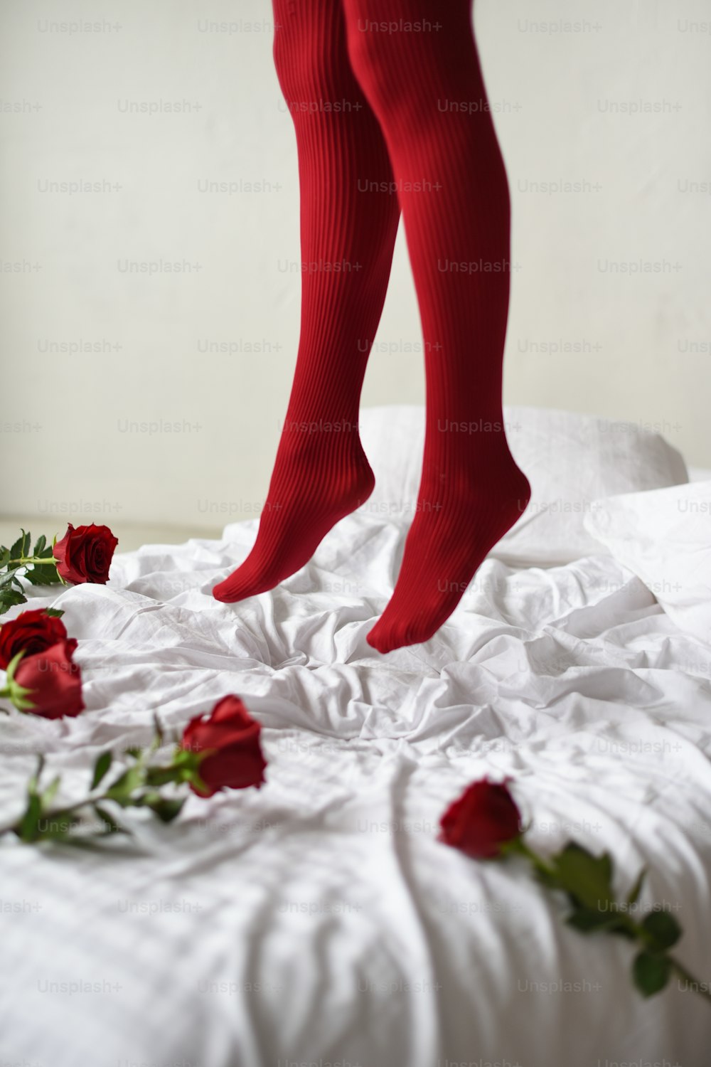 a person standing on a bed with red roses